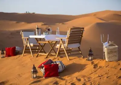 a table and chairs in the sand in the desert at Sahara Starlight Luxury Camp in Merzouga