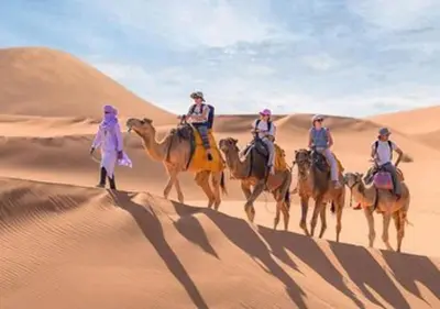 a group of people riding on camels in the desert at Sahara Starlight Luxury Camp in Merzouga
