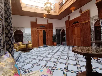 a living room with a tile floor and a chandelier at Riad Joseph in Fès