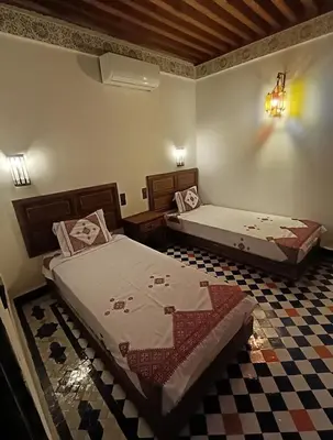 a bedroom with two beds and a checkered floor at Riad Joseph in Fès