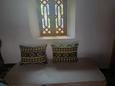 a bench with two pillows under a stained glass window at Riad Joseph in Fès