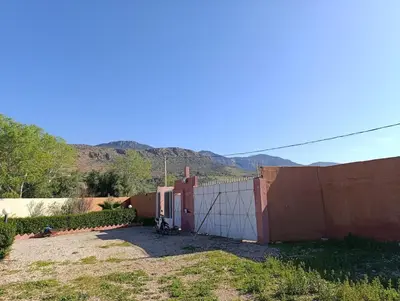 a fence with a white gate in front of a mountain at Villa montysco in Hal Sabek