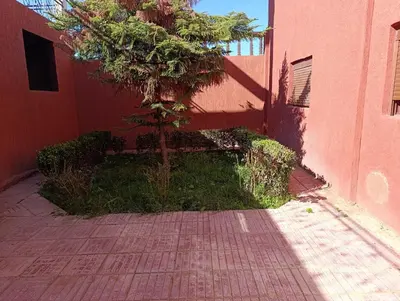 a tree is sitting next to a pink building at Villa montysco in Hal Sabek