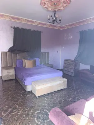 a bedroom with a bed with purple sheets and a chair at Villa montysco in Hal Sabek