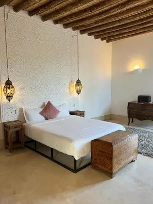 a bedroom with a large bed and a table at Villa les 3 Palmiers B&B in Jdiouat