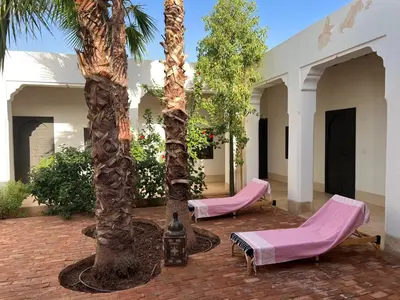 two palm trees and lounge chairs in a courtyard at Villa les 3 Palmiers B&B in Jdiouat