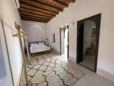 a white bedroom with a bed and a mirror at Villa les 3 Palmiers B&B in Jdiouat