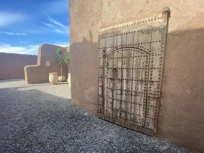 a gate on the side of a building with a desert view at Villa les 3 Palmiers B&B in Jdiouat