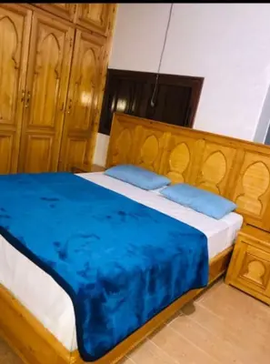 a bedroom with a large wooden bed with blue pillows at villa maya in Ourika