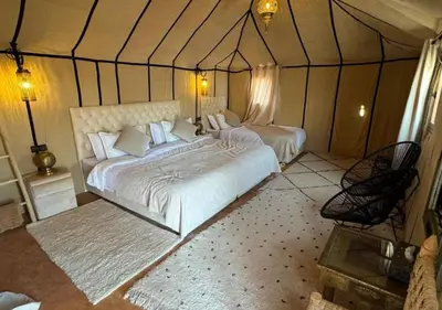 a large bedroom with two beds in a tent at Moroccan luxury camp in Merzouga
