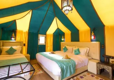 a bedroom with two beds and a tent at Moroccan luxury camp in Merzouga