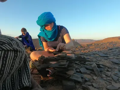 a woman sitting on the rocks in the desert at camp marhaba iriki in Alougoum