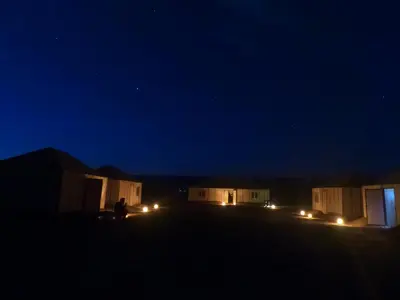 a person standing in front of some buildings at night at camp marhaba iriki in Alougoum