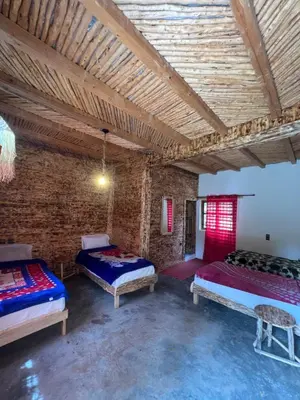 a room with three beds and a brick wall at Gite Cathedrale Imsfrane in Temga
