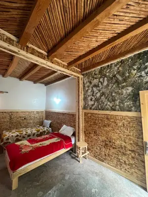 a bedroom with two beds in a room with a stone wall at Gite Cathedrale Imsfrane in Temga