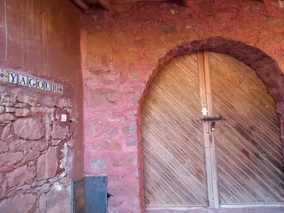 a large wooden door in a brick wall at yagour hebergement in Setti Fatma