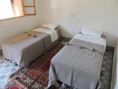a room with two beds and a rug at yagour hebergement in Setti Fatma