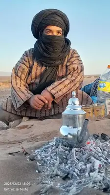 a woman sitting in the sand next to a fire hydrant at Iriki Desert Camp Foum Zguid in Foum Zguid