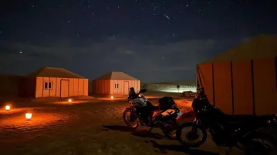 two motorcycles parked in front of some huts at night at Iriki Desert Camp Foum Zguid in Foum Zguid