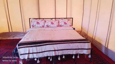 a bed with a pink blanket and pink pillows at Iriki Desert Camp Foum Zguid in Foum Zguid