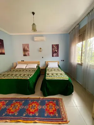 a bedroom with two beds and a window at Dyafat Abla in Ouarzazate
