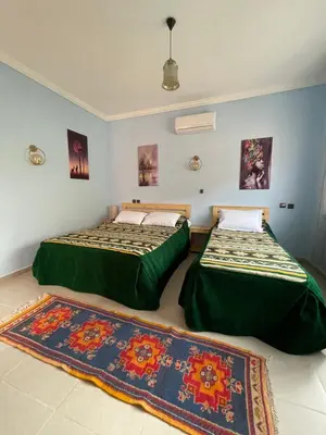two beds in a room with two rugs at Dyafat Abla in Ouarzazate
