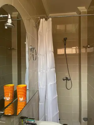 a shower in a bathroom with orange cups on a shelf at Dyafat Abla in Ouarzazate