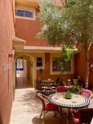 an outdoor patio with tables and chairs and a building at Dyafat Abla in Ouarzazate