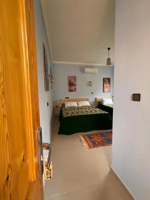a bedroom with a bed with a green comforter at Dyafat Abla in Ouarzazate