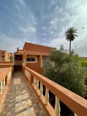a balcony of a house with a palm tree at Dyafat Abla in Ouarzazate