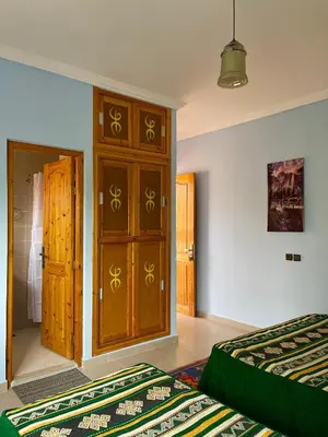 a bedroom with two beds and a wooden cabinet at Dyafat Abla in Ouarzazate