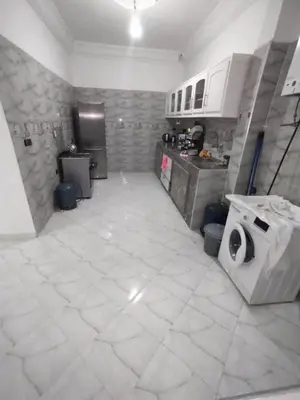 a kitchen with a white tiled floor with a washing machine at apartment for rent by days in Zagora