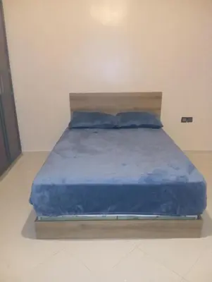 a bed with blue sheets and pillows in a room at Jana in Meknès
