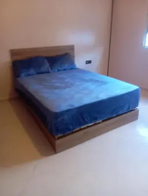a bed in a room with a blue bedsheet at Jana in Meknès