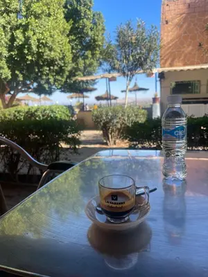 a cup of coffee on a table with a bottle of water at Hôtel Imouzzer in Ourika
