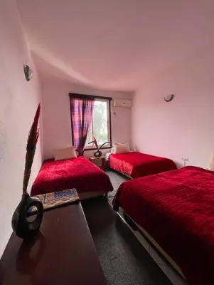a bedroom with two red beds and a window at Hôtel Imouzzer in Ourika