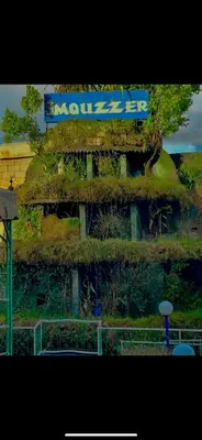 a building covered in moss with a sign on it at Hôtel Imouzzer in Ourika