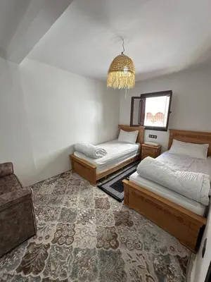 a bedroom with two beds and a chandelier at Taghazout Hostel in Oulad Akkou