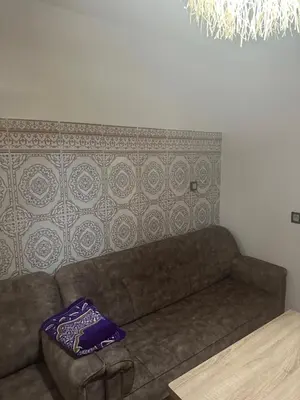 a couch in a living room with a purple pillow at Taghazout Hostel in Oulad Akkou