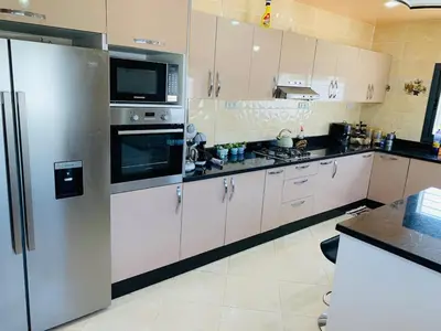 a kitchen with white cabinets and stainless steel appliances at Al confort in Fès