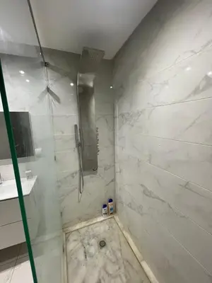 a bathroom with a shower with white marble walls at Luxueux appartement centre ville wifi 200 Mo in Fès