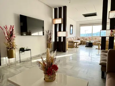 a living room with a couch and a tv on the wall at Luxueux appartement centre ville wifi 200 Mo in Fès