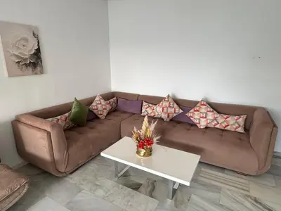a living room with a brown couch and a table at Luxueux appartement centre ville wifi 200 Mo in Fès