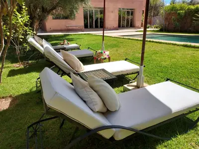 a group of lounges in the grass near a pool at Villa Azuréa with pool 4 bedrooms and 2 living rooms in Ourika