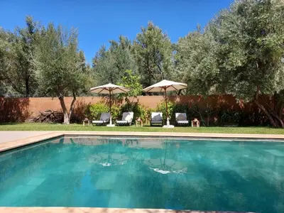 a swimming pool with chairs and umbrellas in a yard at Villa Azuréa with pool 4 bedrooms and 2 living rooms in Ourika