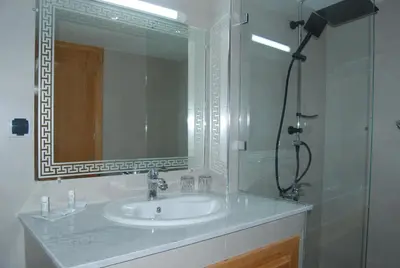 a bathroom with a sink and a mirror and a shower at Hôtel Asswar Al Madina in Fès