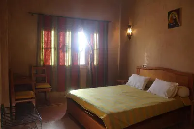 a bedroom with a bed and a window with a curtain at Dar Lamrani in Rissani
