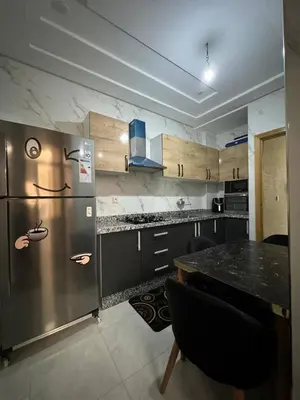 a kitchen with a stainless steel refrigerator and a table at Dar location luxury in Meknès