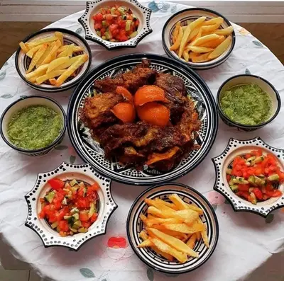 a table topped with plates of food and french fries at Desert Berber Luxury Camp in Merzouga