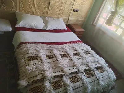 a bed in a bedroom with a white blanket on it at almou auberge imilchil in Imilchil